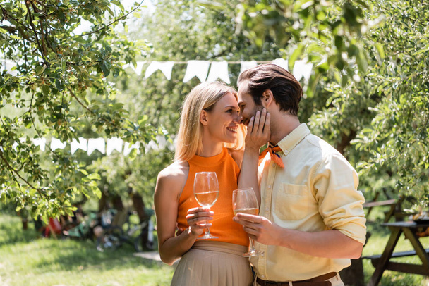 Side view of stylish couple holding glasses of wine in summer park  - Foto, Imagen