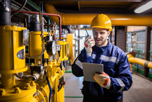 Factory worker serviceman checking natural gas pipeline installations and using tablet computer. - Photo, image