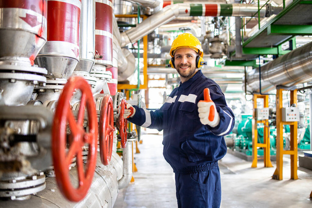 Retrato de engenheiro trabalhador da planta de aquecimento em pé por gasodutos naturais e segurando polegares para cima. - Foto, Imagem