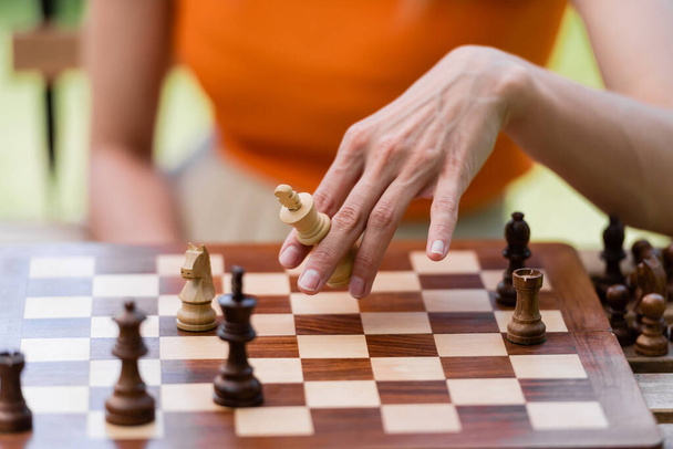 Cropped view of woman holding chess figure near board in park  - Photo, Image