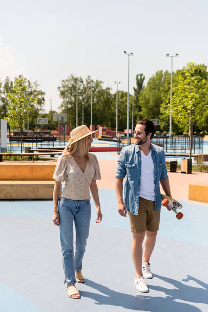 Cheerful couple with longboard walking in skate park  - Fotografie, Obrázek