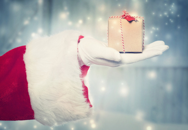 Santa Claus holidng a small Christmas present - Фото, зображення