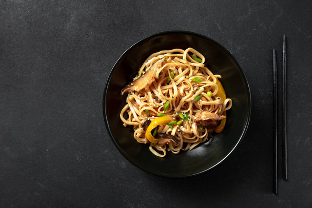 Asian noodles in a bowl on a dark background.Vegetarian noodles, vegetable noodles Hakka Noodles or Chow Mein in a black bowl on a dark background - Photo, Image
