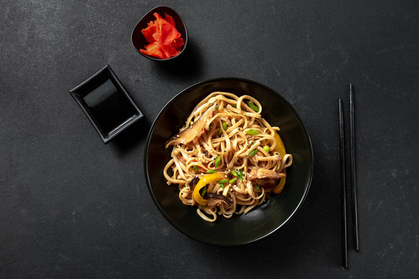 Vegetarian Schezwan Noodles or Vegetable Hakka Noodles or Chow Mein in black bowl at dark background. Schezwan Noodles is indo-chinese cuisine hot dish with udon noodles, vegetables. - Photo, Image