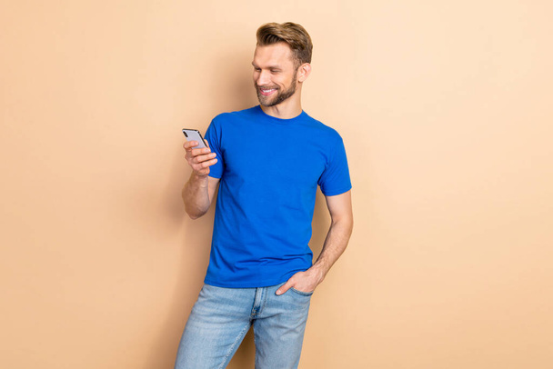 Photo of young cheerful guy use mobile type share repost comment fast connection 4g isolated over beige color background. - 写真・画像