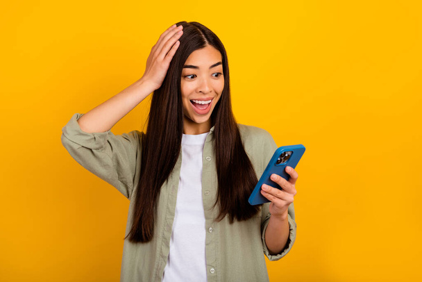 Photo of overjoyed crazy young blogger girl see many likes on her new post isolated on yellow color background. - Foto, Bild