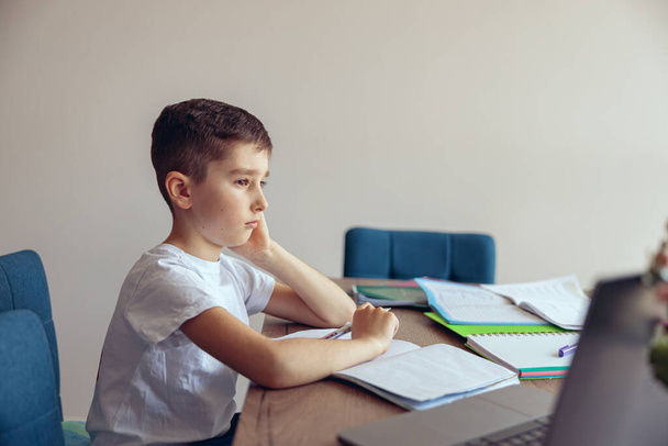 Side view on sad Caucasian boy pupil doing homework and being lazy. Learning at home. Schoolboy. - Foto, imagen
