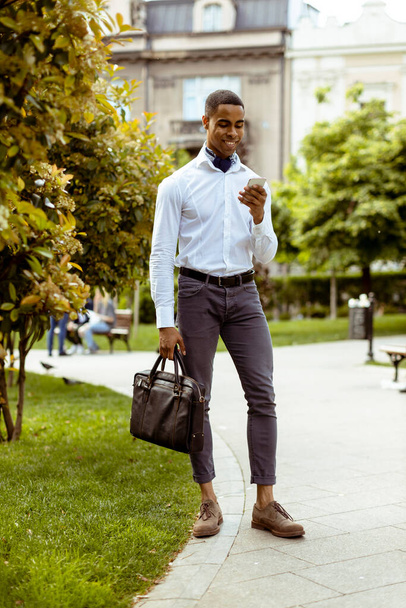 Юний афроамериканський бізнесмен, який користується мобільним телефоном на вулиці. - Фото, зображення