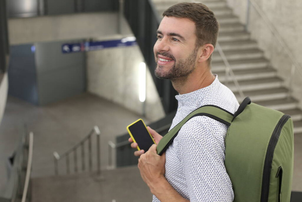 detail-up portrét pohledného mladého muže s batohem na vlakovém nádraží během cesty - Fotografie, Obrázek