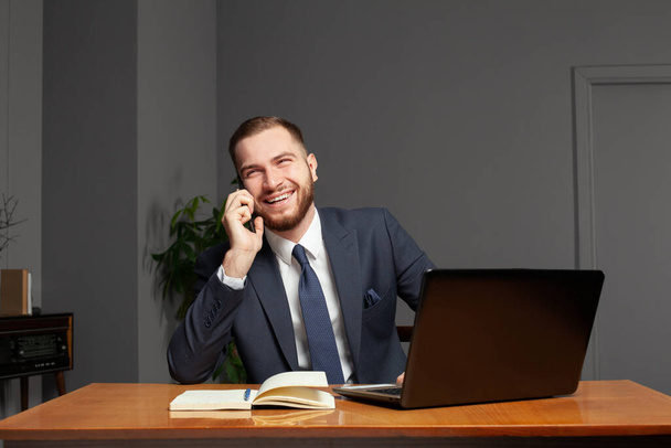 Šťastný obchodník v kanceláři mluví po telefonu - Fotografie, Obrázek