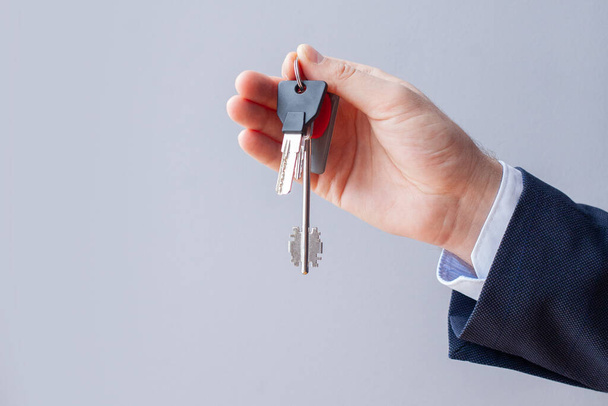 House keys in male hand on white background. Real estate concept - Foto, Imagen