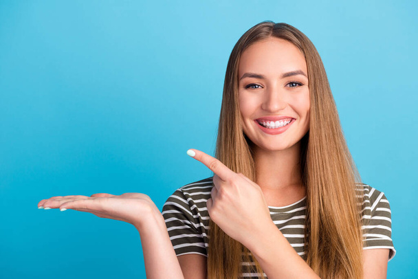 Portrait of charming positive person direct finger empty space hand palm isolated on blue color background. - Foto, immagini