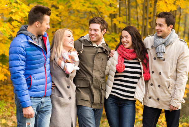 group of smiling men and women in autumn park - Фото, изображение