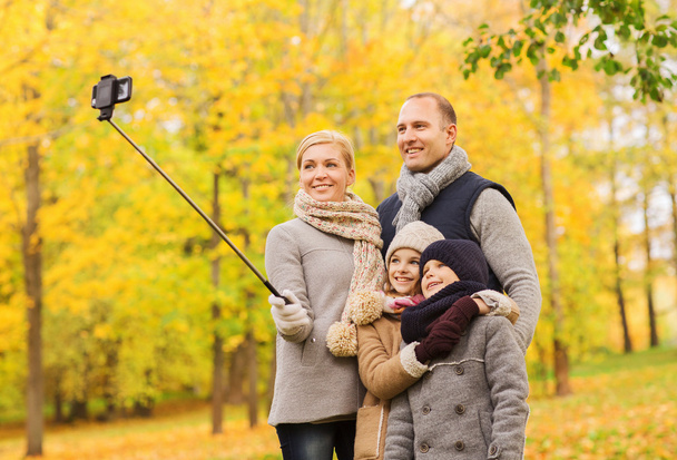 happy family with smartphone and monopod in park - Valokuva, kuva