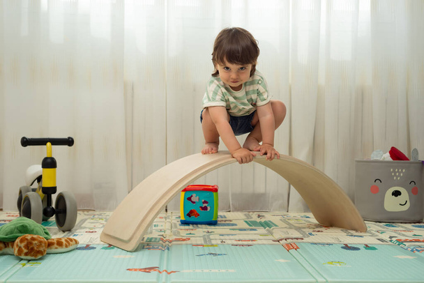 Enfant regardant la caméra sur un tableau d'équilibre dans une salle de jeux montessori. - Photo, image