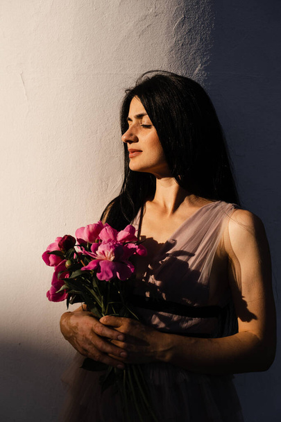 Женщина с пигментацией кожи витилиго на руках отдыхает букет цветов пионы. Сезонные заболевания кожи - Фото, изображение