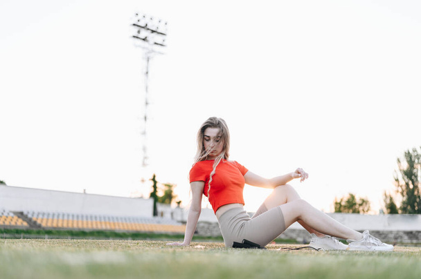 Dívka vstává z trávy v Red Top. Provazový výcvik. Atletická dlouhosrstá žena leží na zelené trávě. Rozmazané pozadí. - Fotografie, Obrázek