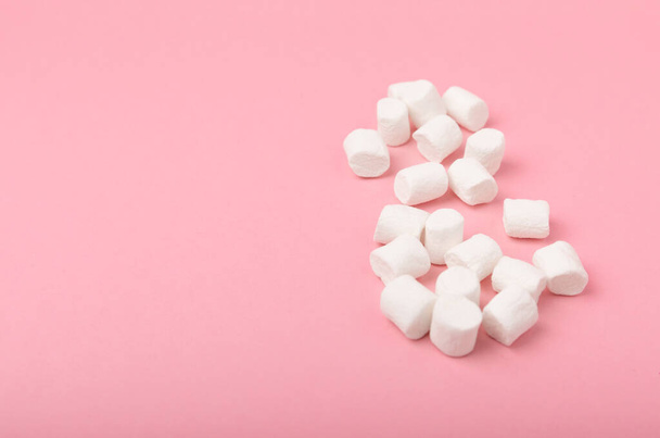 Loose marshmallows on a pink background. White marshmallow flat lay. Sweets and snacks for a snack. Chewing candies close-up. Copy space. Place for text. Winter food concept. - Foto, imagen