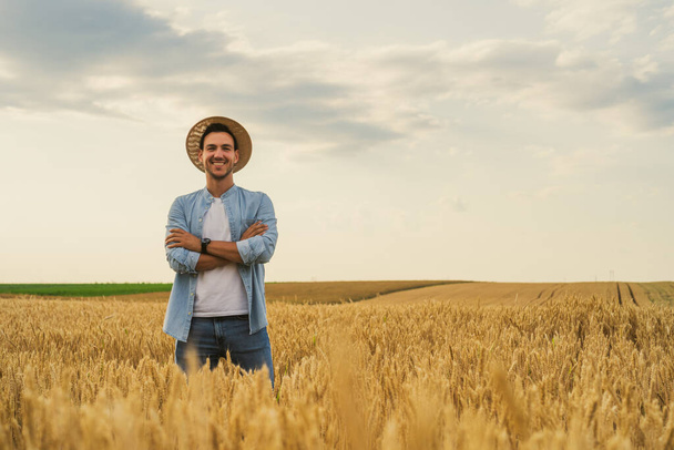 Happy farmer is standing in his growing wheat field. - Valokuva, kuva