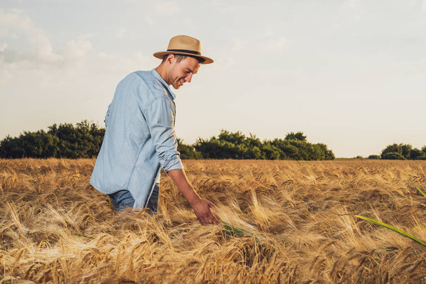 Happy farmer is standing in his growing barley field. - Fotografie, Obrázek