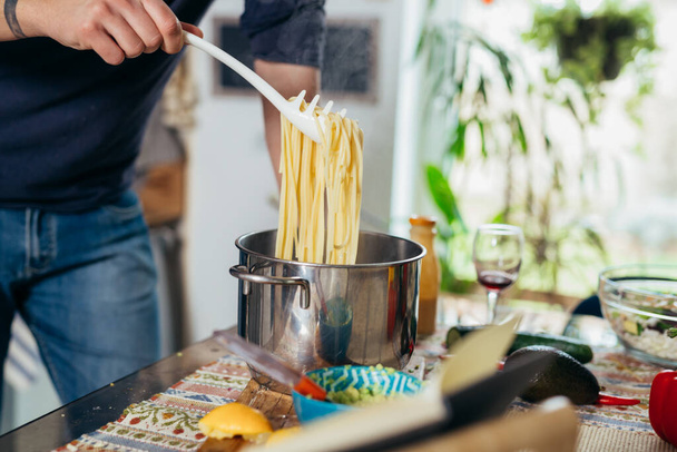 close up man preparing spaghetti in kitchen - Zdjęcie, obraz