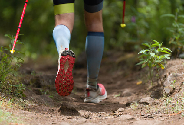 Athlete man running mountain marathon along a forest trail with and poles - Foto, imagen