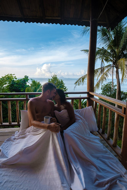 Bir kaç erkek ve kadın, sabah Tayland 'da sırt çantalı bir kulübede uyanan ve Railay plajı Krabi Tayland' da kahve içen bir sahil kulübesinin balkonunda. - Fotoğraf, Görsel