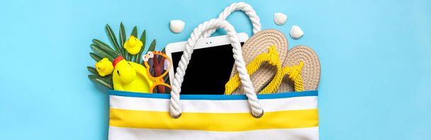Yüzme aksesuarları - çizgili moda plaj çantası, siyah gözlük, beyaz tablet, palmiye yaprağı, mavi arka planda sarı parmak arası terlik.. - Fotoğraf, Görsel