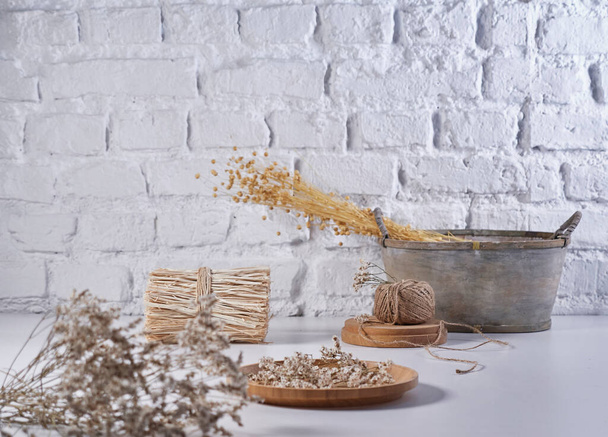 Fiore di cotone e vaso borsa di vimini di stile vegetale sul tavolo bianco, sfondo muro di mattoni, natura morta, decorazione. - Foto, immagini