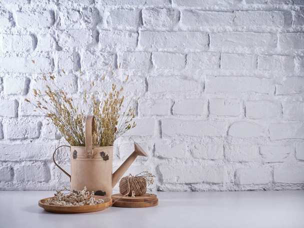 白いテーブルの上の植物スタイルの綿の花とウィッカーバッグ花瓶、レンガの壁の背景、静物、装飾. - 写真・画像