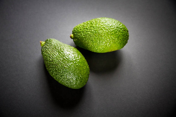 Two fresh avocados isolated on a black background - Фото, зображення
