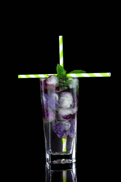 Glas met ijs, koud water, verse munt en eetbare bloemen  - Foto, afbeelding