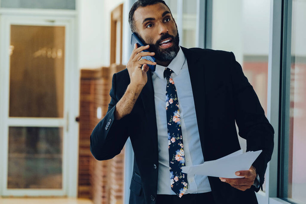 bell'uomo d'affari afro-americano in giacca e cravatta che parla sullo smartphone mentre è in carica - Foto, immagini