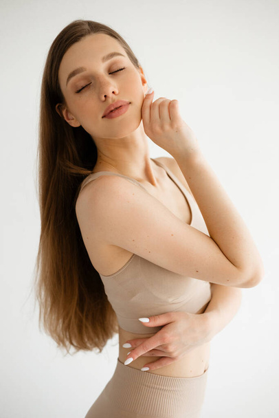Beautiful girl with long hair in flesh-colored compression clothing. High quality photo - Valokuva, kuva