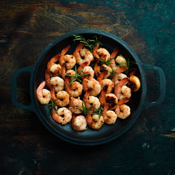 Fried shrimp with garlic and lemon in a pan. Seafood. On a black stone background. - Фото, изображение