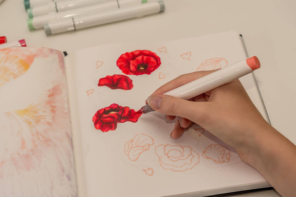 Hand drawing a red poppy wreath sketch in a sketchbook with alcohol based sketch drawing markers. Remembrance Day and Anzac day. - Photo, Image
