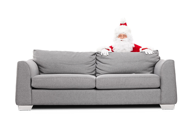Santa Claus hiding behind a sofa  - Фото, зображення