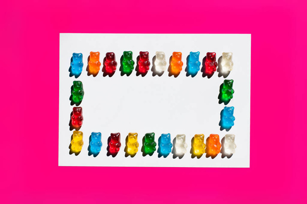 Flat lay with colorful gummy bears on white and pink surface - Foto, Bild
