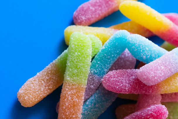 Close up view of gummy sweets with sugar on blue background  - Foto, afbeelding