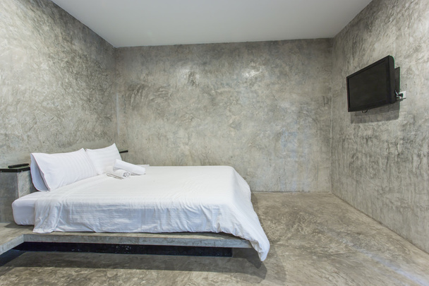 cama blanca con pared de cemento gris
 - Foto, Imagen