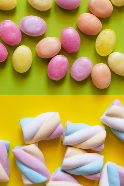 Top view of candies and marshmallows on green and yellow background  - Foto, afbeelding