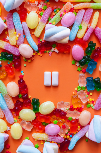 Flat lay with chewing gums near jelly sweets and candies on orange background  - Фото, зображення