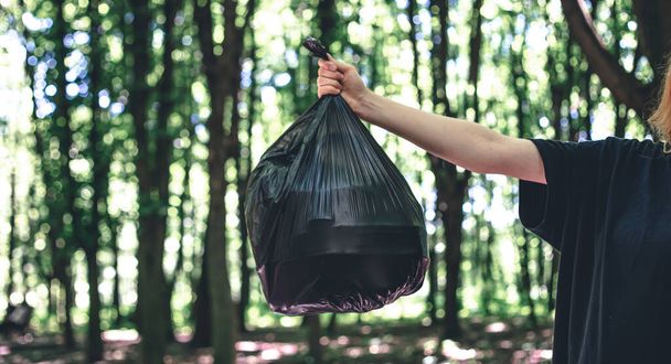 森を背景にしたゴミ袋「クローズアップ」「エコロジーと自然への愛」. - 写真・画像