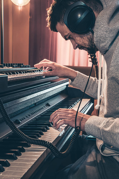 Mužský hudebník hraje hudební klávesy ve sluchátkách, hudební koncept. - Fotografie, Obrázek