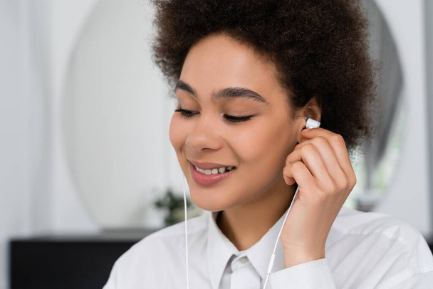 happy african american woman listening music in wired earphones  - Foto, afbeelding