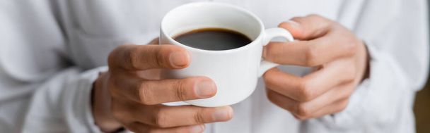 vista recortada de la mujer sosteniendo taza de café negro en las manos, pancarta - Foto, imagen