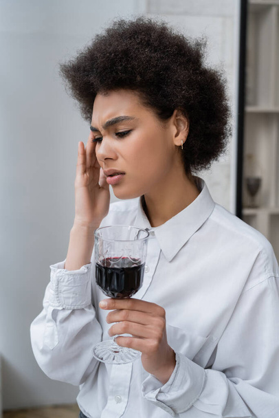 απογοητευμένη Αφροαμερικανή γυναίκα που κρατάει ένα ποτήρι κόκκινο κρασί  - Φωτογραφία, εικόνα