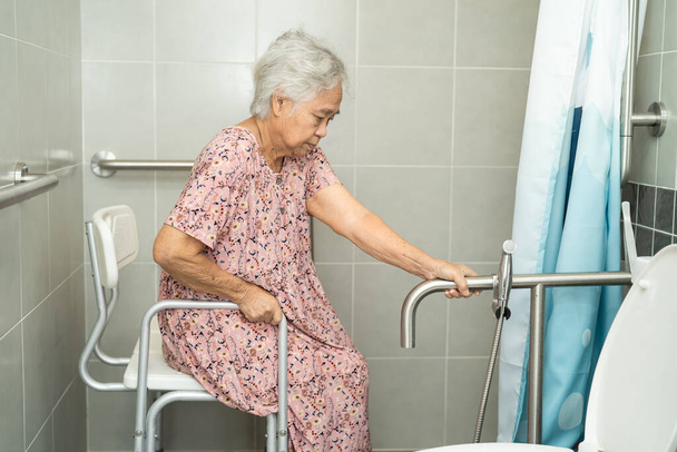 Asiatique senior ou vieille dame femme patient utilisation toilettes salle de bain poignée sécurité dans la salle d'hôpital de soins infirmiers, concept médical fort sain. - Photo, image