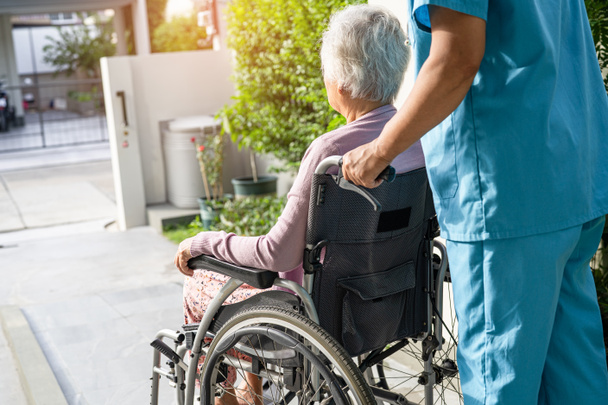 Φροντιστής βοήθεια και φροντίδα ασιατική ανώτερος ή ηλικιωμένη ηλικιωμένη γυναίκα ασθενή κάθεται σε αναπηρική καρέκλα στη ράμπα στο νοσηλευτικό νοσοκομείο, υγιή ισχυρή ιατρική έννοια - Φωτογραφία, εικόνα