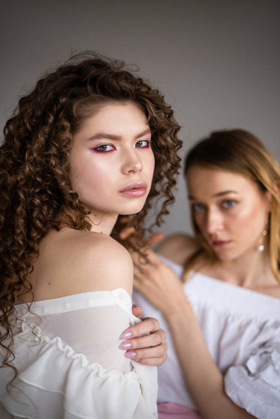 Twee mode vrouwelijke modellen op een grijze achtergrond studio portret van twee jonge stijlvolle meisjes poseren - Foto, afbeelding